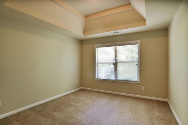 carpeted empty room featuring a tray ceiling, baseboards, and visible vents