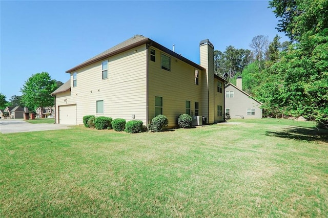 view of side of home featuring driveway, a lawn, and a chimney