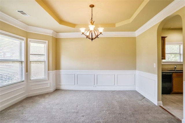 unfurnished room featuring visible vents, arched walkways, an inviting chandelier, a tray ceiling, and light carpet