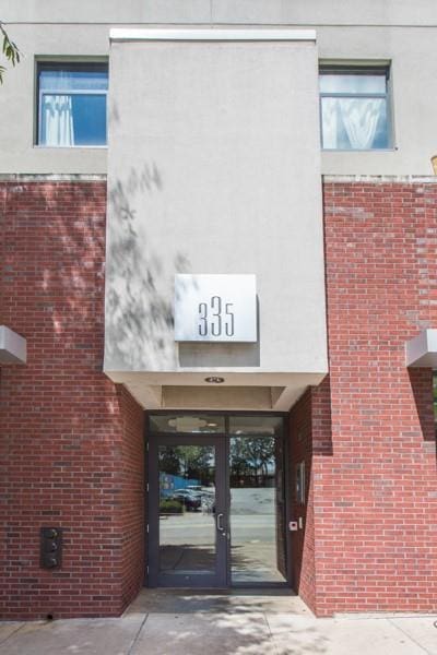 view of exterior entry with concrete driveway and brick siding