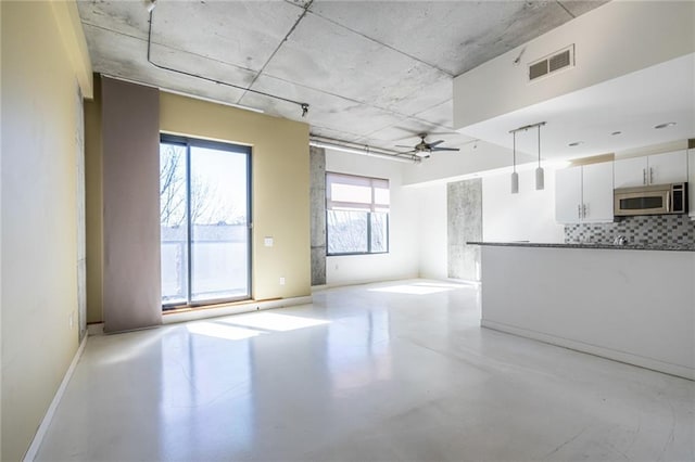 unfurnished living room featuring visible vents, baseboards, concrete floors, and a ceiling fan