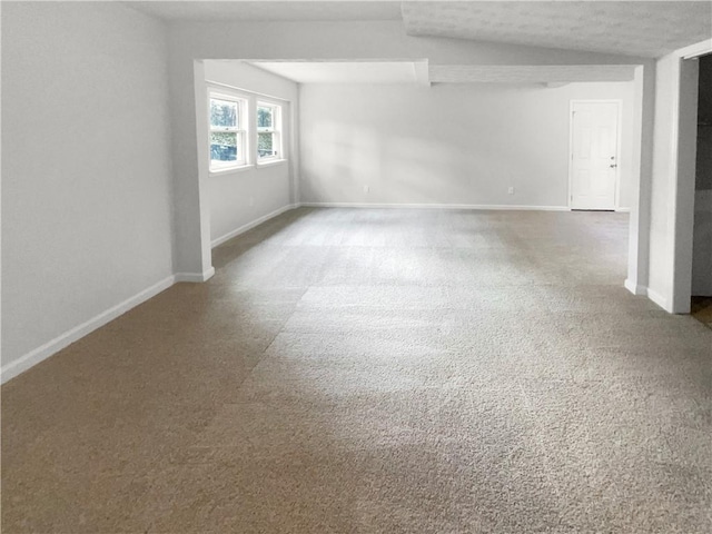 empty room featuring a textured ceiling, carpet floors, and lofted ceiling