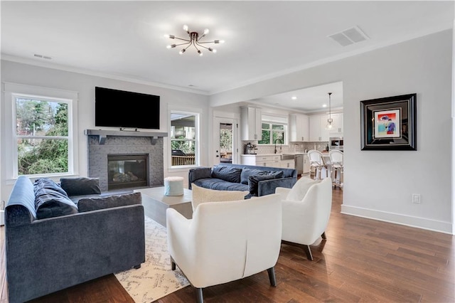 living room with ornamental molding, dark wood-style flooring, visible vents, and a healthy amount of sunlight