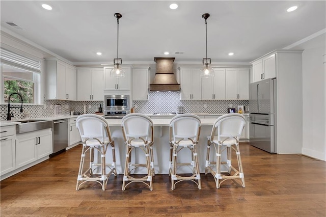 kitchen featuring a kitchen bar, appliances with stainless steel finishes, custom exhaust hood, and a sink