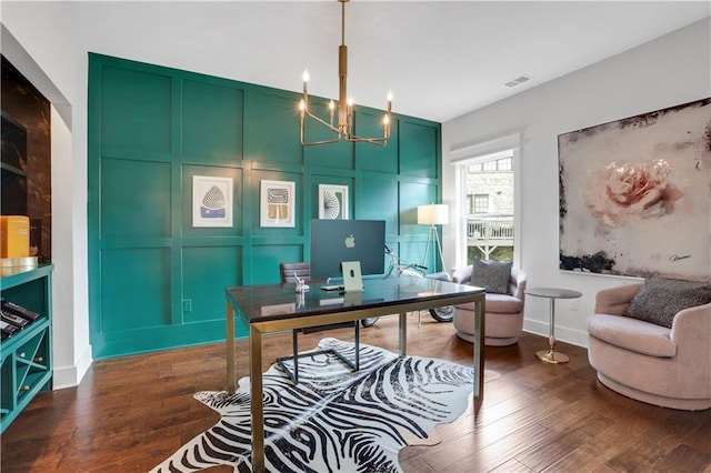 office space featuring dark wood finished floors, visible vents, a decorative wall, a chandelier, and baseboards