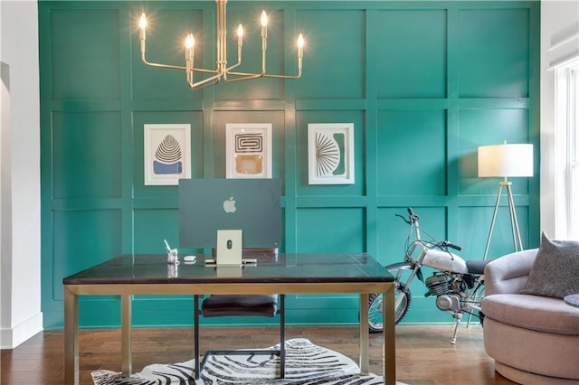 home office with a notable chandelier, a decorative wall, and wood finished floors