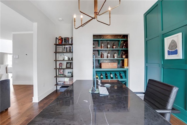 dining area featuring a chandelier, dark wood finished floors, and baseboards