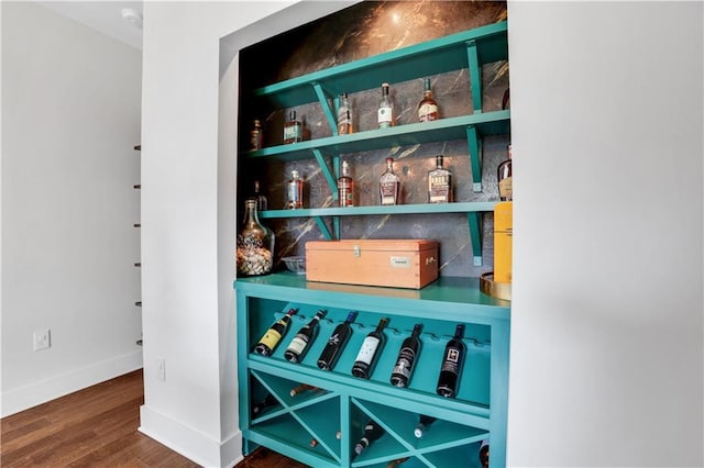 interior space with a dry bar, baseboards, and wood finished floors