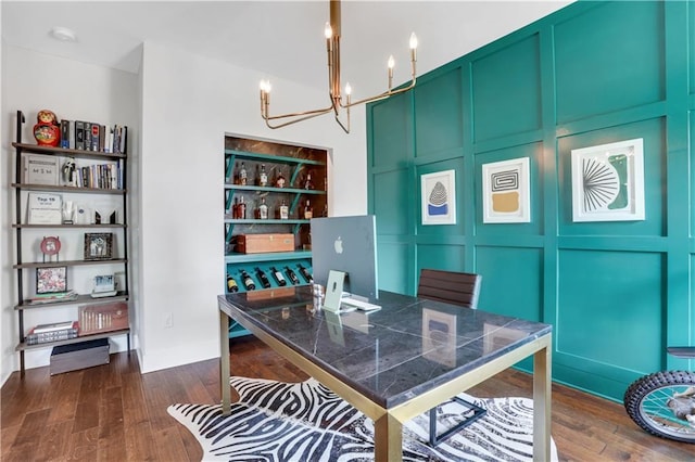 office area with an inviting chandelier, a decorative wall, and dark wood-style flooring