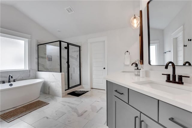 bathroom featuring lofted ceiling, a freestanding tub, vanity, marble finish floor, and a shower stall