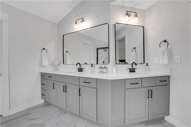 bathroom featuring marble finish floor, a sink, baseboards, and double vanity