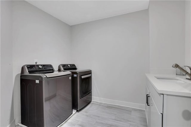 laundry room with washer and clothes dryer, a sink, cabinet space, and baseboards