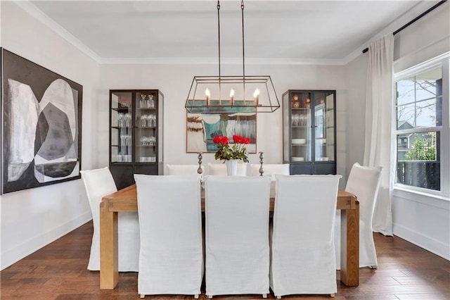 dining space with baseboards, dark wood-style flooring, a chandelier, and crown molding