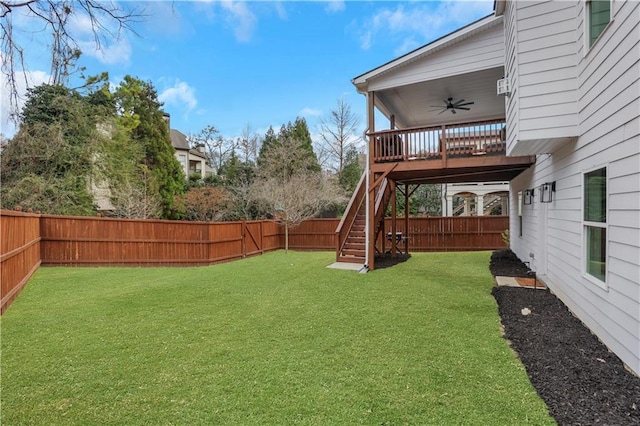 view of yard with a fenced backyard, ceiling fan, and stairs