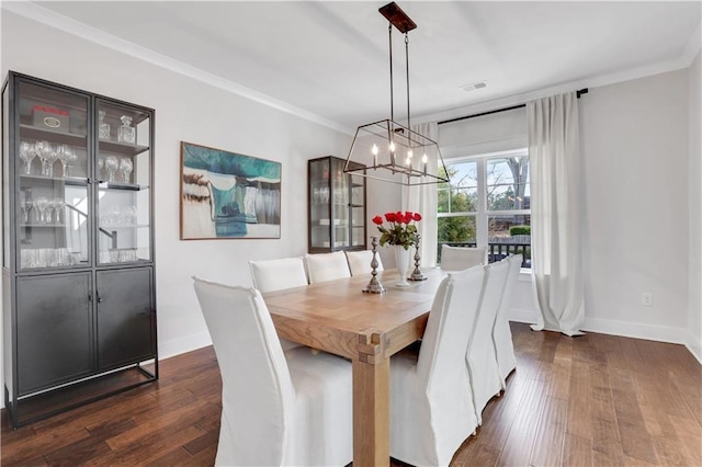 dining area featuring ornamental molding, a chandelier, dark wood finished floors, and baseboards