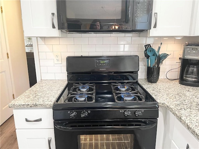 kitchen featuring tasteful backsplash, light stone countertops, white cabinets, and black appliances