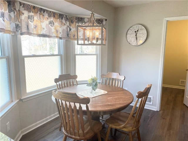 dining space with dark wood-type flooring and a chandelier