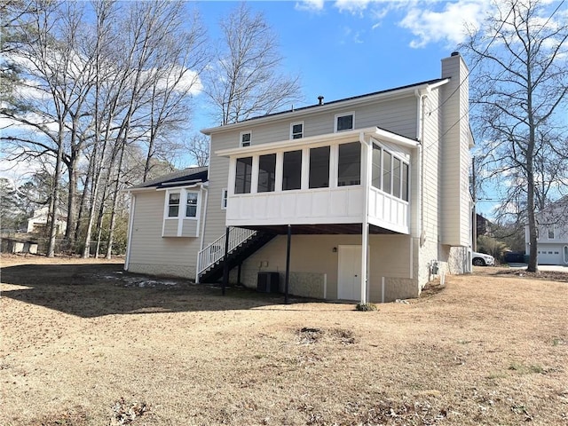 rear view of house with central AC unit and a sunroom