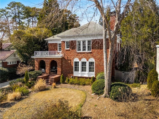 view of front of home featuring brick siding, fence, and a chimney