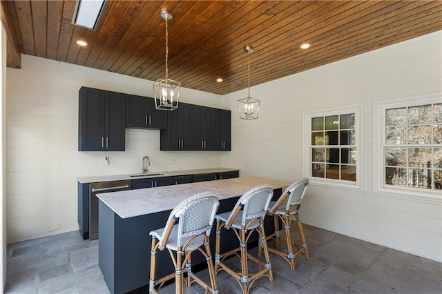 kitchen featuring a sink, dark cabinetry, stainless steel dishwasher, a center island, and decorative light fixtures