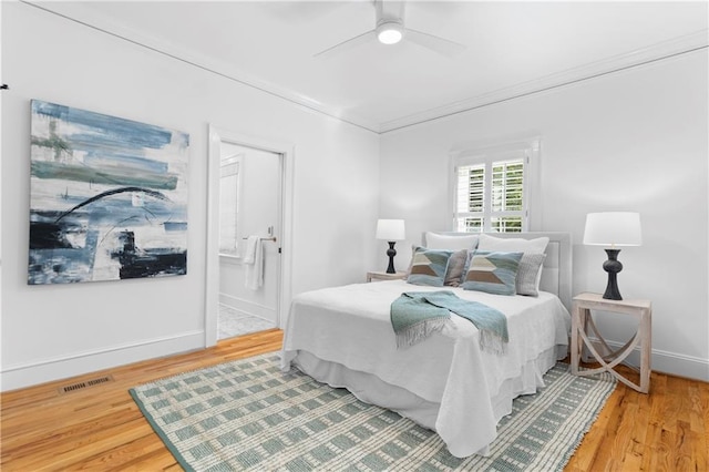 bedroom with baseboards, visible vents, wood finished floors, and ornamental molding