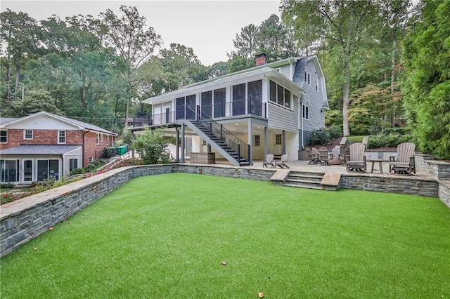 rear view of house featuring a fire pit, a patio, a sunroom, a chimney, and stairway