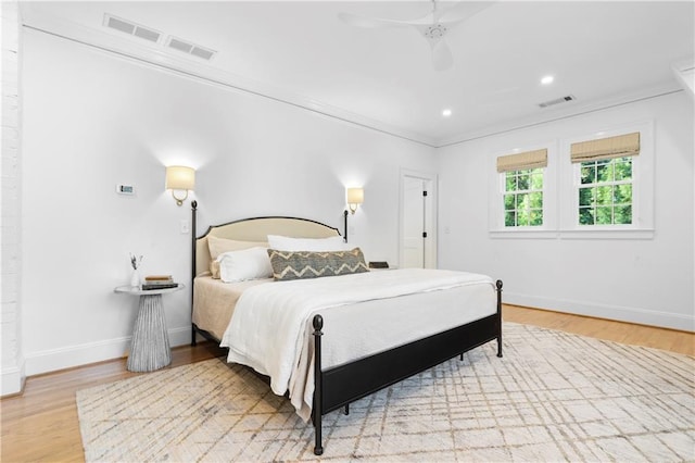 bedroom featuring baseboards, visible vents, wood finished floors, and ornamental molding