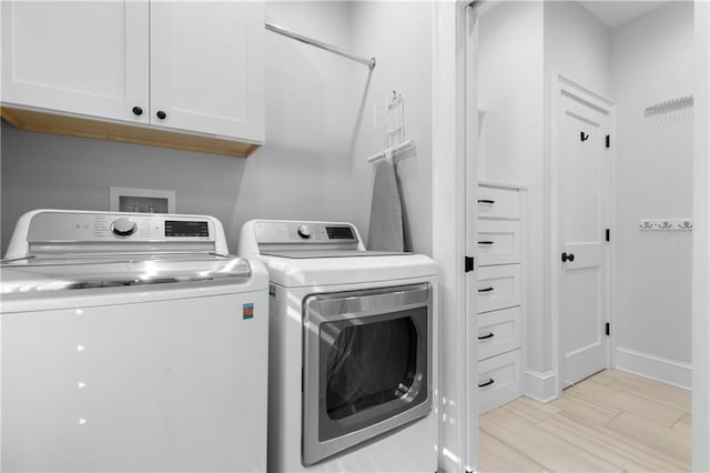 laundry room with cabinet space, light wood-style flooring, baseboards, and separate washer and dryer