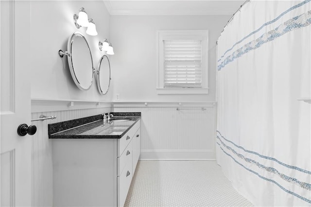 bathroom featuring a wainscoted wall, crown molding, and vanity