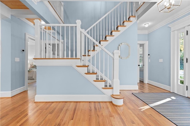 entrance foyer with ornamental molding, stairway, baseboards, and wood finished floors