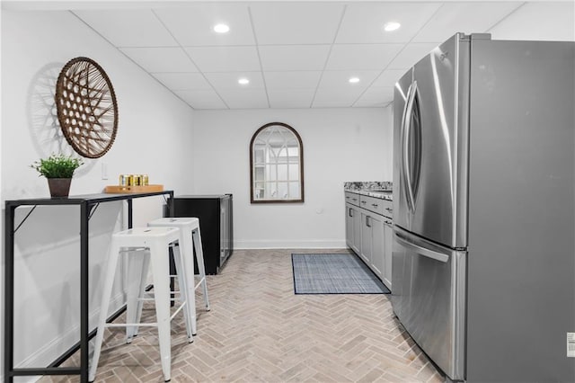 kitchen featuring brick floor, a paneled ceiling, recessed lighting, freestanding refrigerator, and baseboards