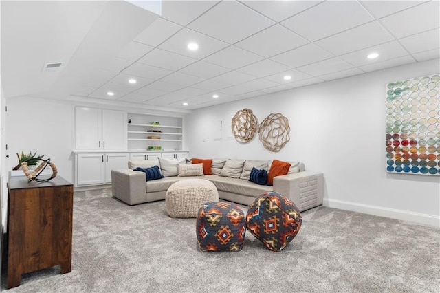 living room with built in shelves, recessed lighting, visible vents, light carpet, and baseboards