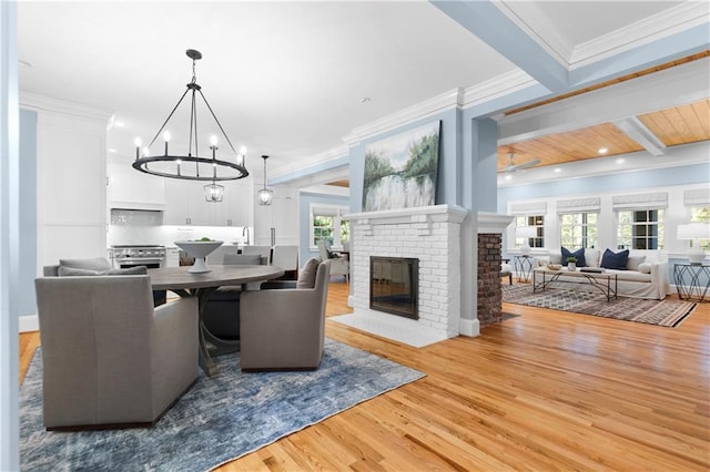 dining area with wood finished floors, crown molding, a brick fireplace, beam ceiling, and recessed lighting