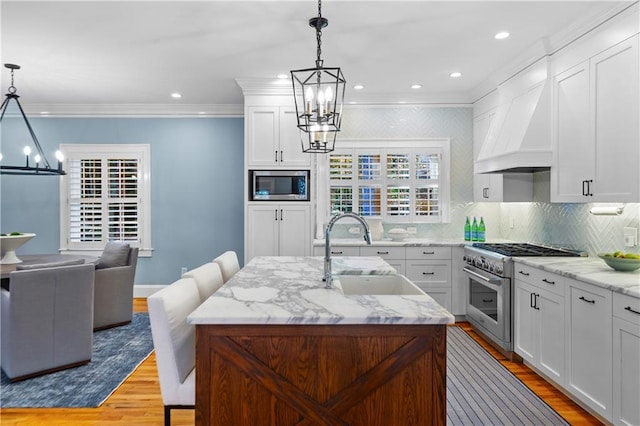 kitchen with stainless steel appliances, an island with sink, and decorative light fixtures