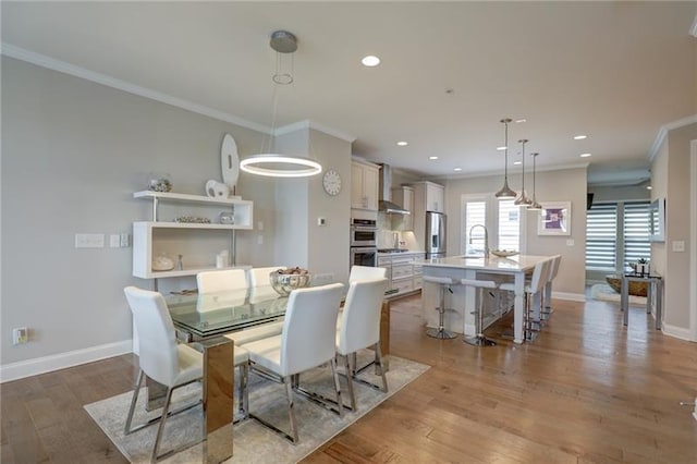 dining area featuring baseboards, light wood-style flooring, and crown molding