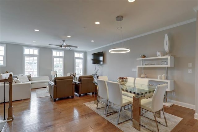 dining area with light wood-style floors and crown molding