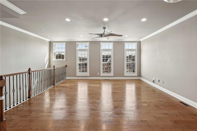 spare room featuring wood-type flooring, crown molding, baseboards, and a ceiling fan