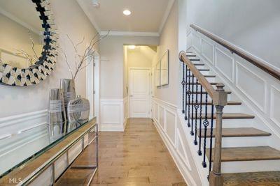 stairs with a wainscoted wall, ornamental molding, wood finished floors, a decorative wall, and recessed lighting