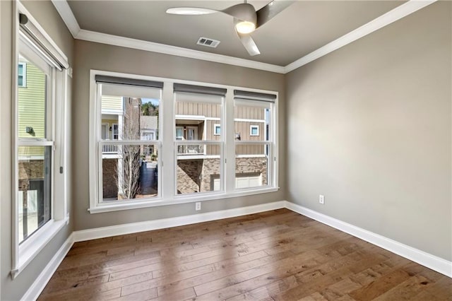 unfurnished room featuring dark wood-type flooring, visible vents, crown molding, and baseboards