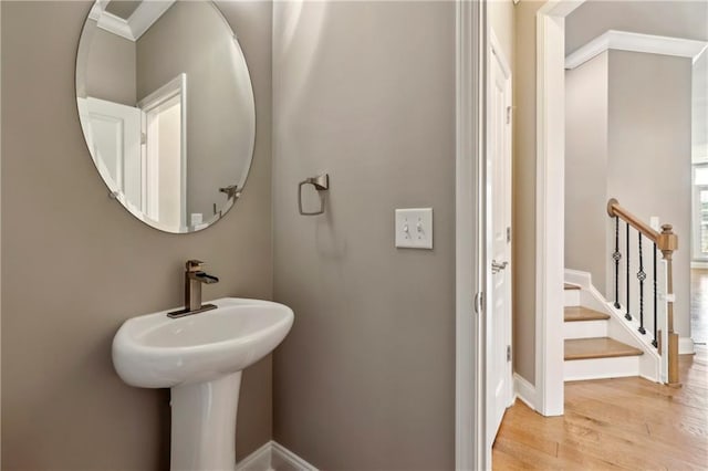 bathroom with ornamental molding, wood finished floors, and baseboards