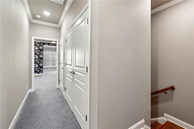 hall with carpet floors, baseboards, ornamental molding, and an upstairs landing