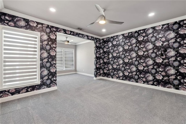 unfurnished room featuring wallpapered walls, visible vents, ceiling fan, carpet, and crown molding