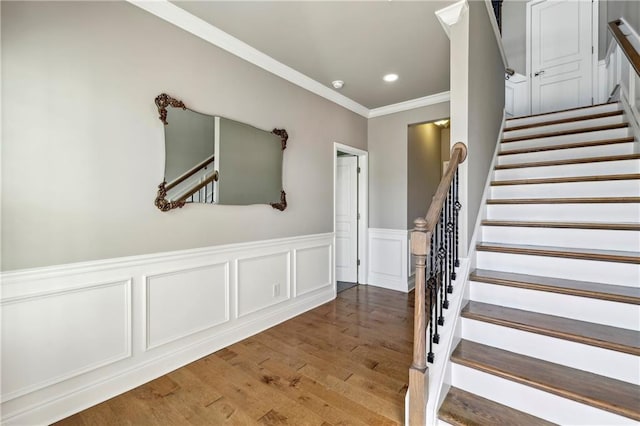 stairway featuring wainscoting, ornamental molding, wood finished floors, and recessed lighting