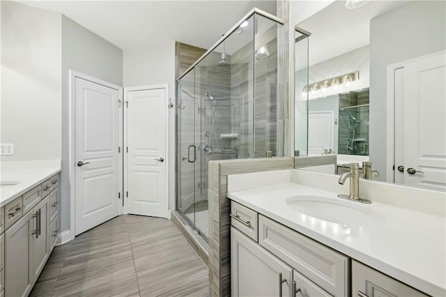 full bath featuring a stall shower, two vanities, and a sink