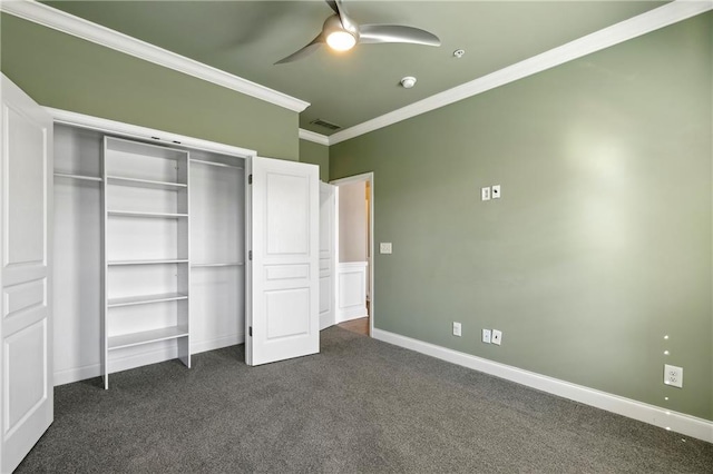 unfurnished bedroom with dark colored carpet, a closet, visible vents, ornamental molding, and baseboards