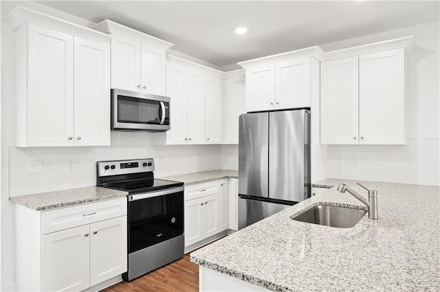 kitchen featuring a sink, stainless steel appliances, wood finished floors, and white cabinets