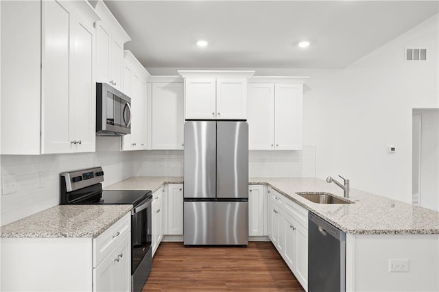 kitchen featuring dark wood-style floors, a peninsula, a sink, appliances with stainless steel finishes, and white cabinetry