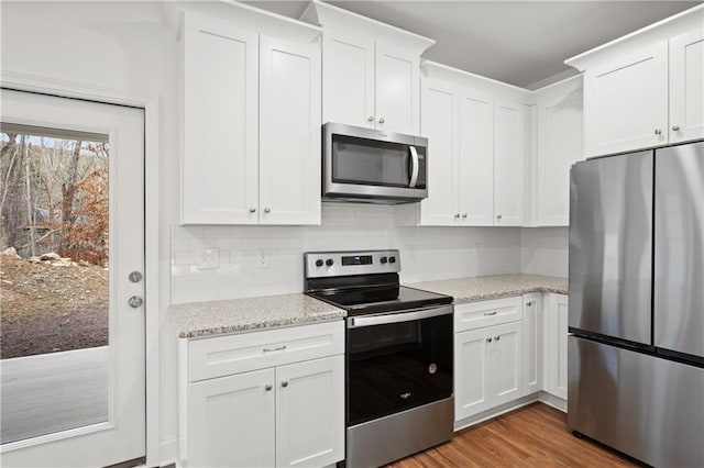 kitchen featuring white cabinets, wood finished floors, and stainless steel appliances