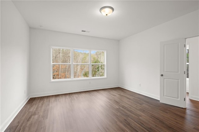 spare room with visible vents, baseboards, and dark wood-style floors