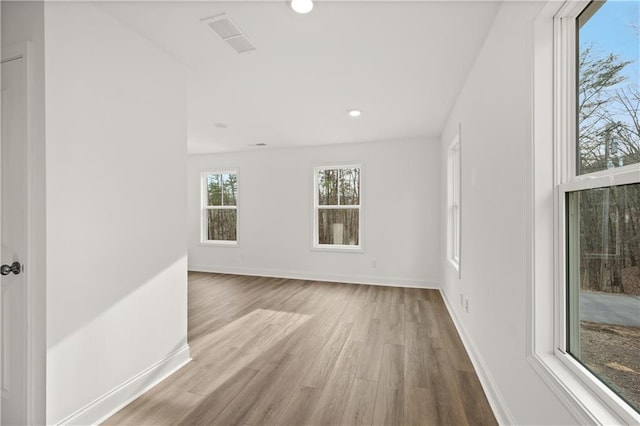 unfurnished room featuring recessed lighting, wood finished floors, visible vents, and baseboards